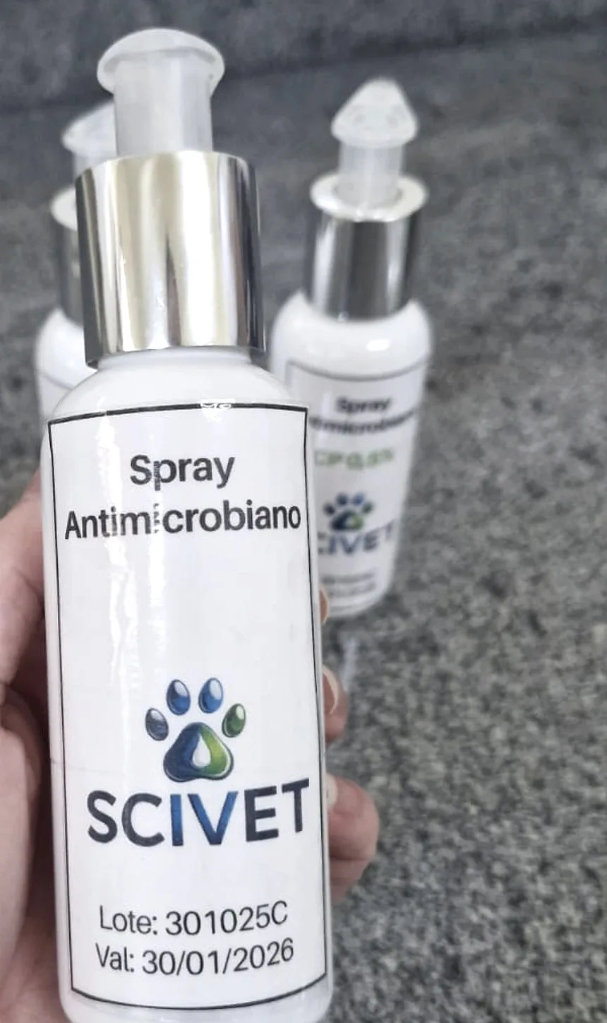 Frasco do spray antimicrobiano da Scivet, segurado com luvas de laboratório, sobre a bancada.